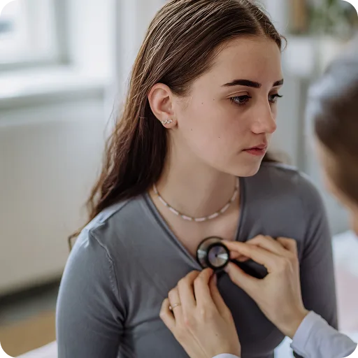 Doctor listening to a teenage girl's back with a stethoscope