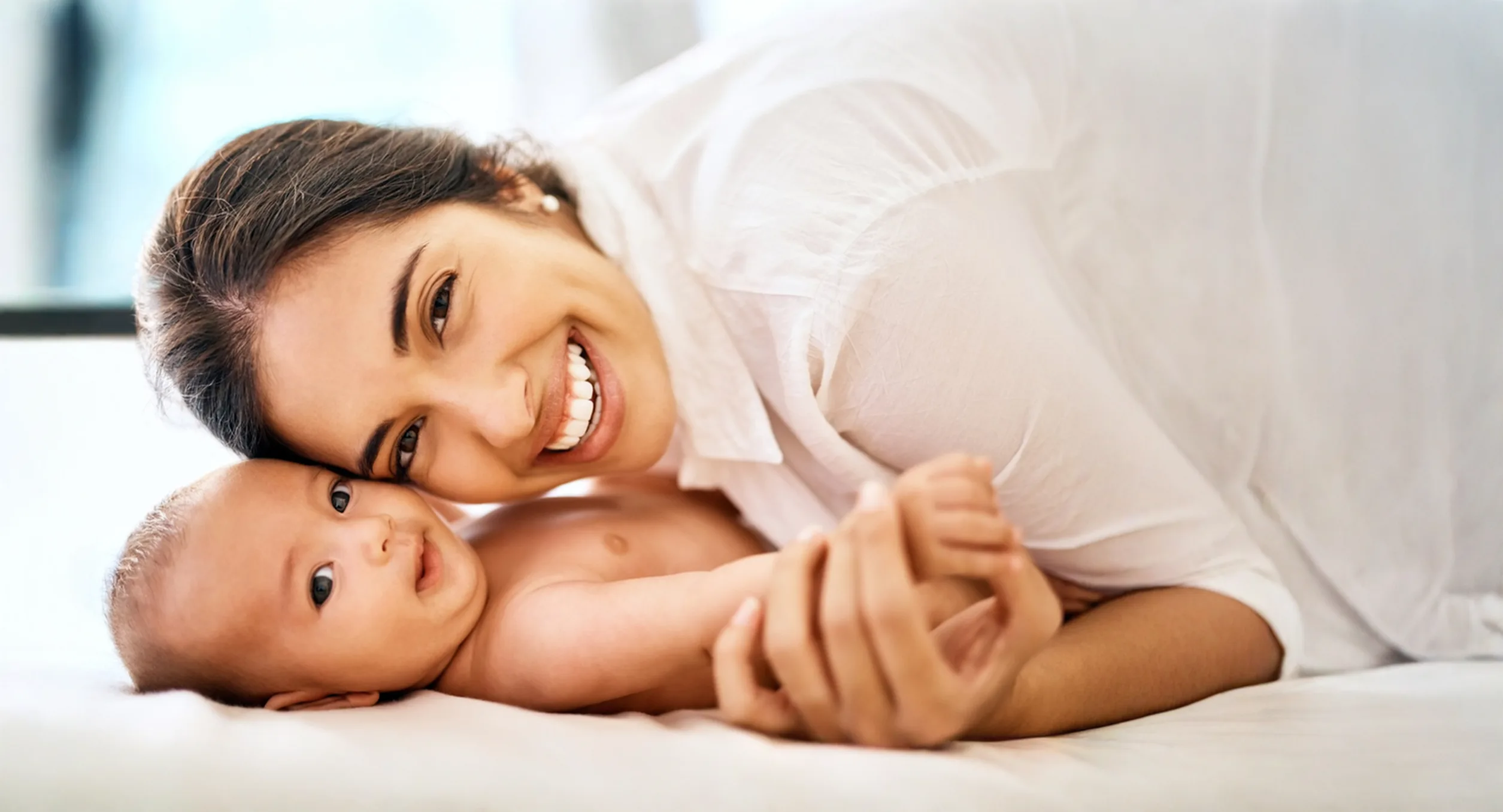 Mother lying beside a smiling baby