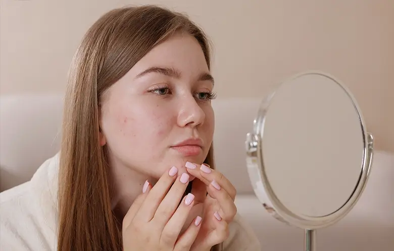 Teenage girl looking at her skin in a mirror