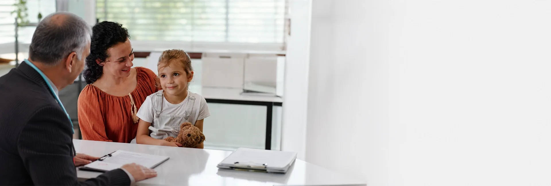 Paediatrician at a desk with a mother and child