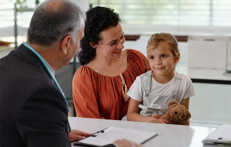 Paediatrician at a desk with a mother and child