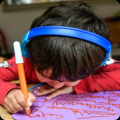 Child wearing headphones colouring with crayons
