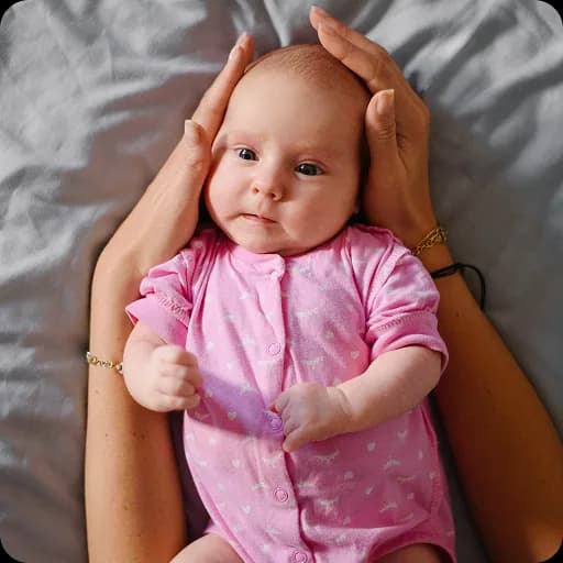 Baby in a pink outfit lying on its back