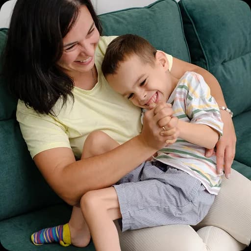 Mother cuddling a young child on a sofa