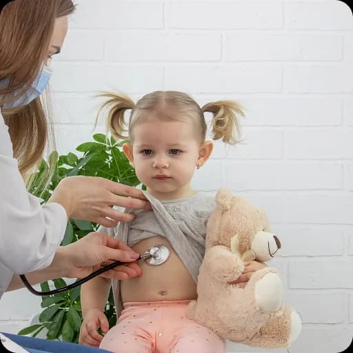 Doctor examining a toddler holding a teddy
