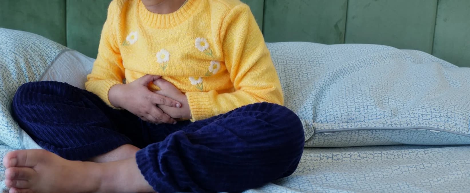 Child holding their tummy sitting on a sofa