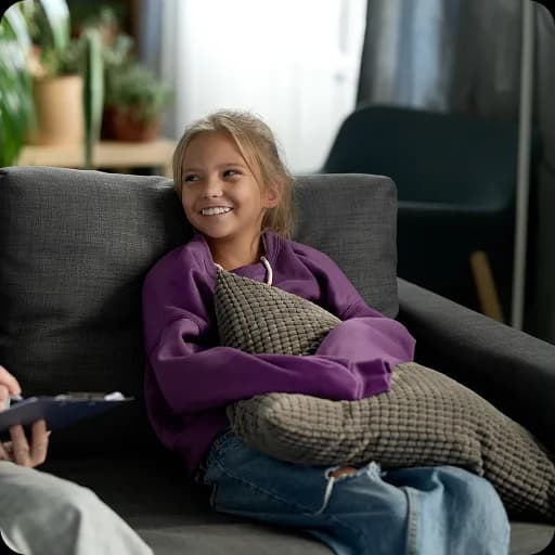 Girl sitting on a sofa hugging her knees