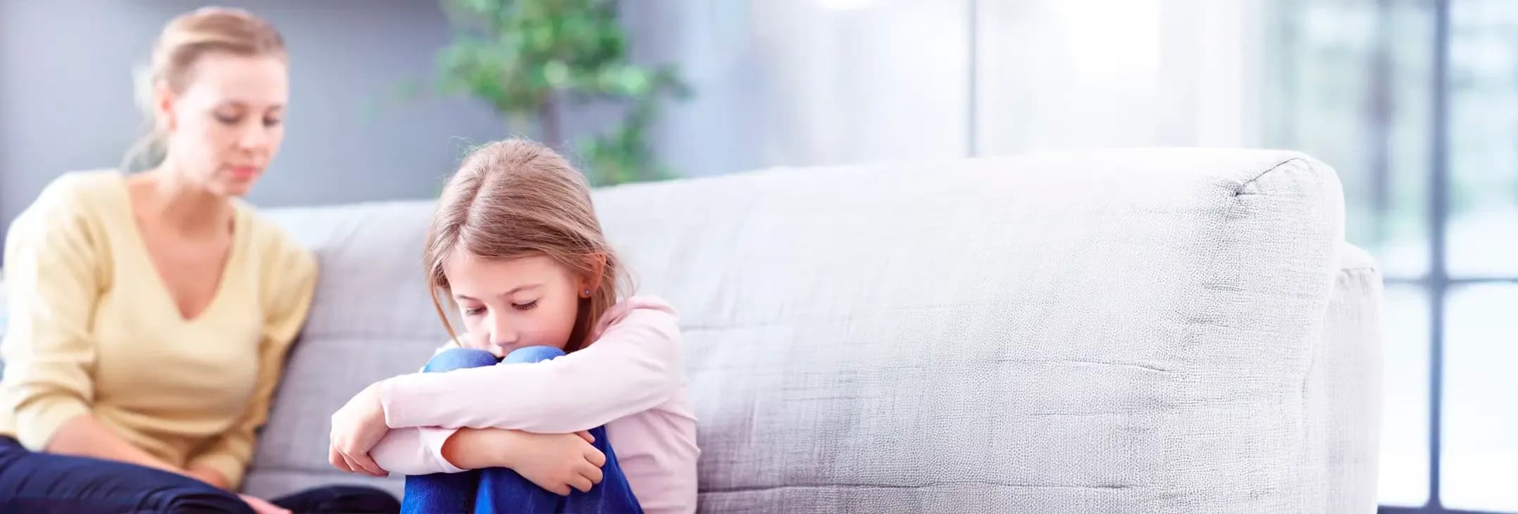 Mother comforting a sad girl on a sofa