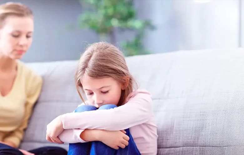 Mother comforting a sad girl on a sofa