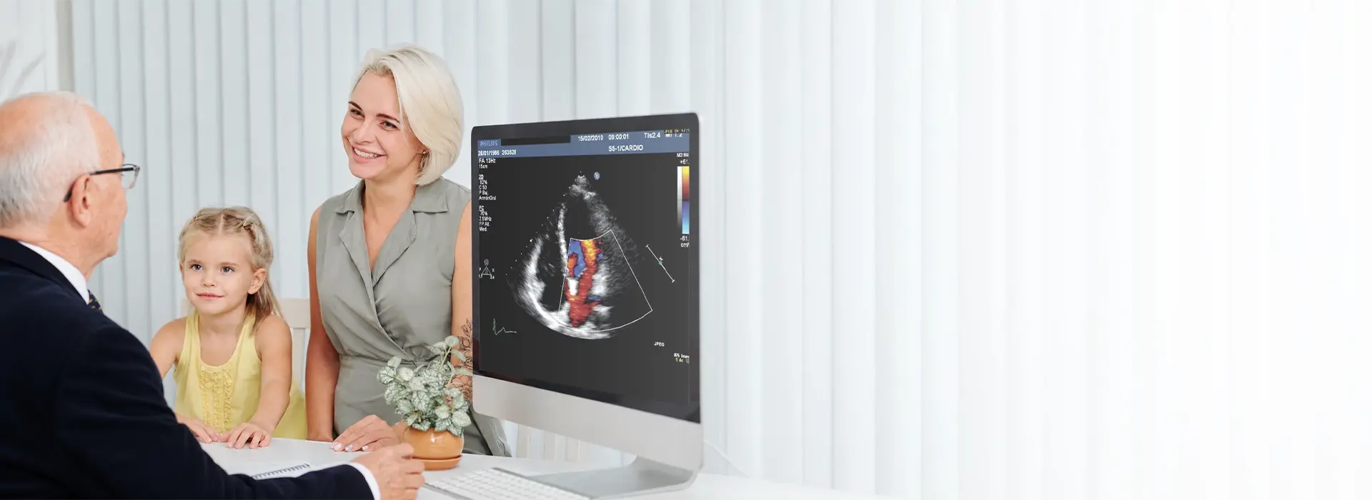 Paediatrician showing a heart scan on screen to a mother and child