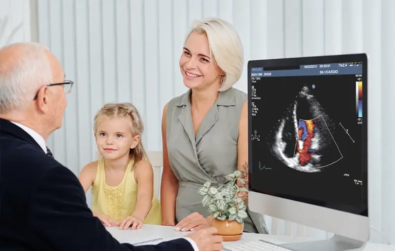 Paediatrician showing a heart scan on screen to a mother and child