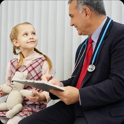 Paediatrician with a young girl holding a teddy