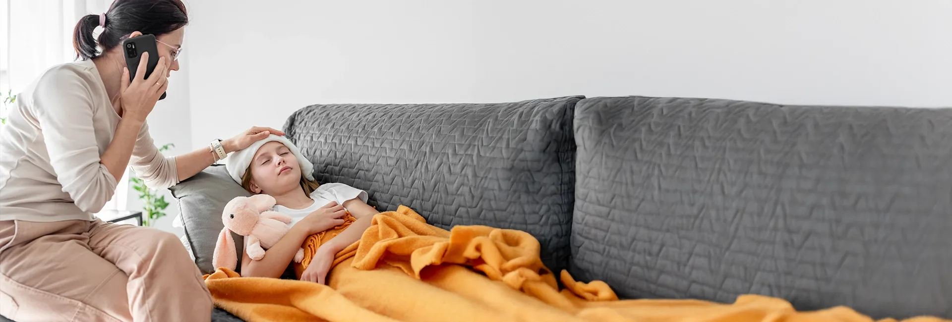 Mother caring for an unwell child on a sofa