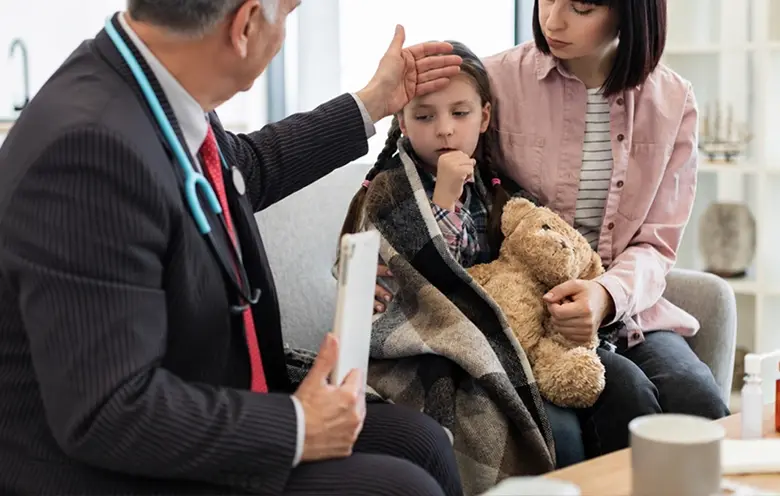 Paediatrician examining a girl with her mother