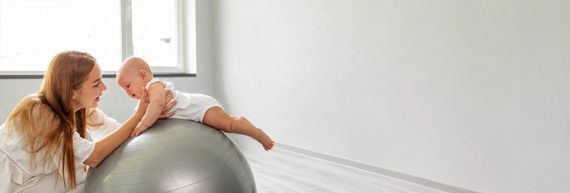 Mother supporting a baby on an exercise ball