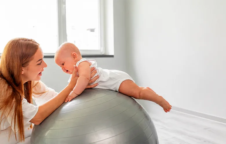 Mother supporting a baby on an exercise ball