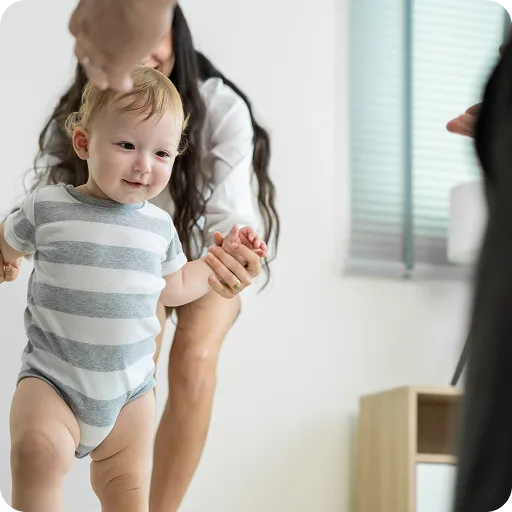 Toddler learning to walk holding an adult's hands