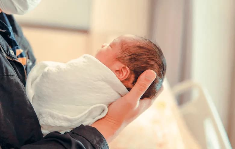 Newborn baby being held by a parent
