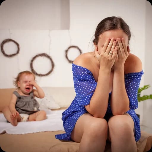 Mother with her head in her hands beside a baby