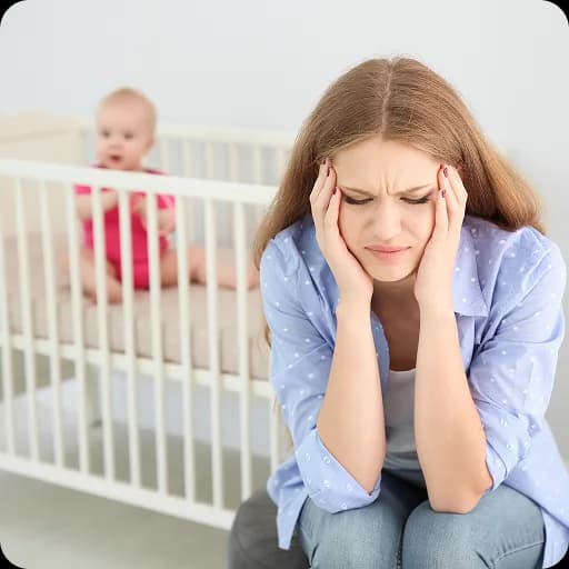 Tired mother sitting beside a cot