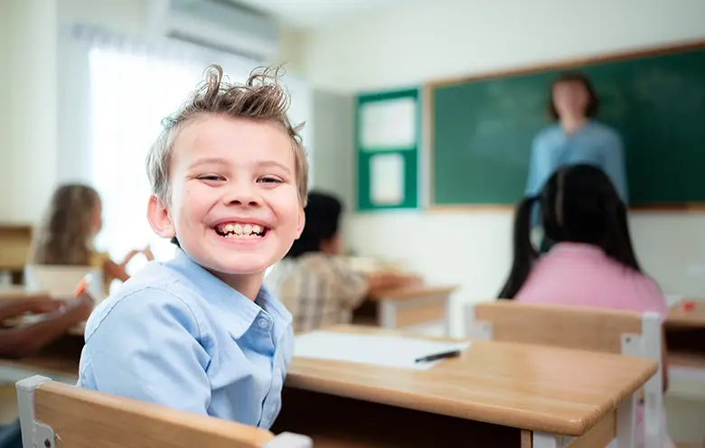 Smiling boy at a classroom desk